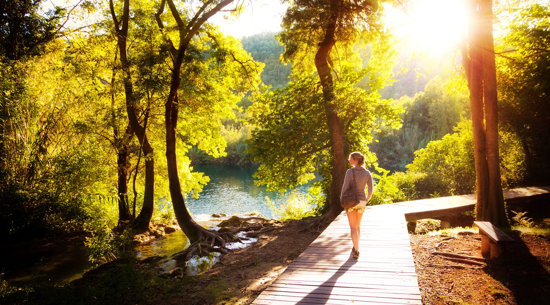 Lady walking through wooded area on wood deck.