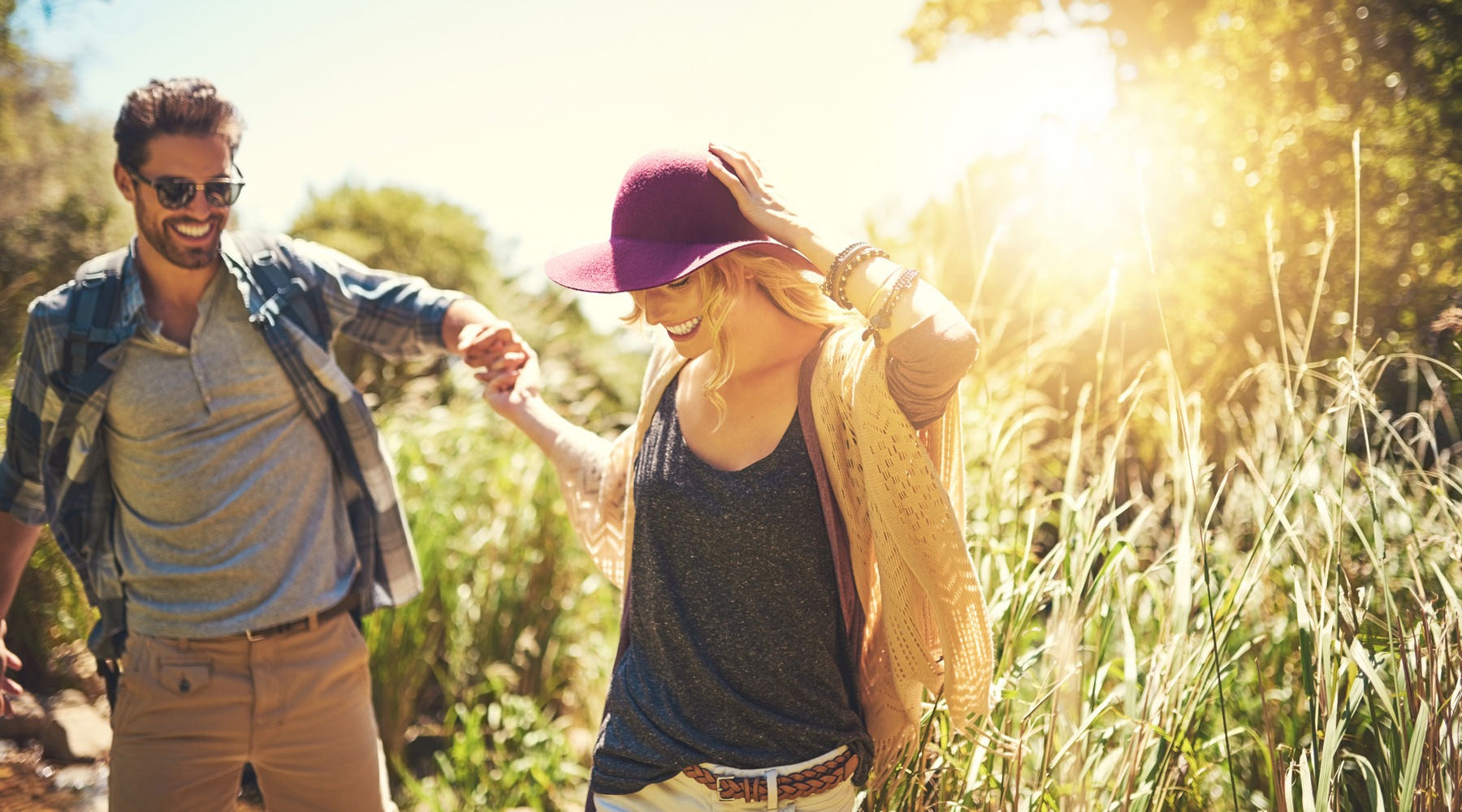 Man and woman walking through brushy area.